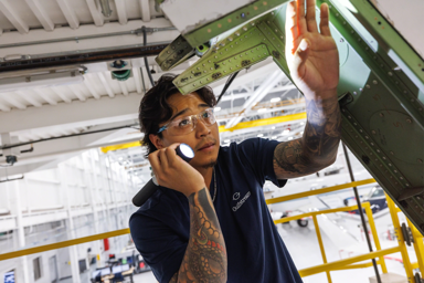 A worker inspecting machinery with a flashlight in a manufacturing facility